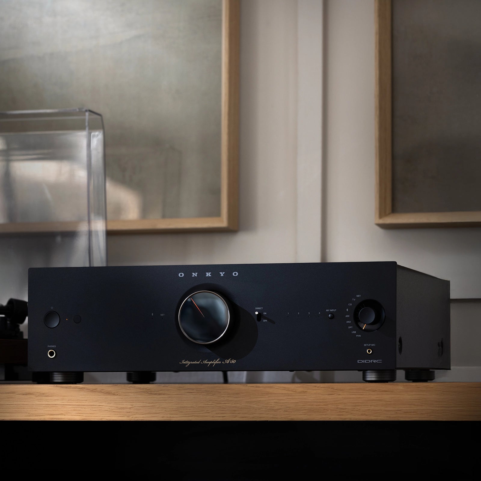 Onkyo Icon A-50 stereo amplifier in black placed on a shelf next to a turntable, showcasing its sleek design and control knobs.