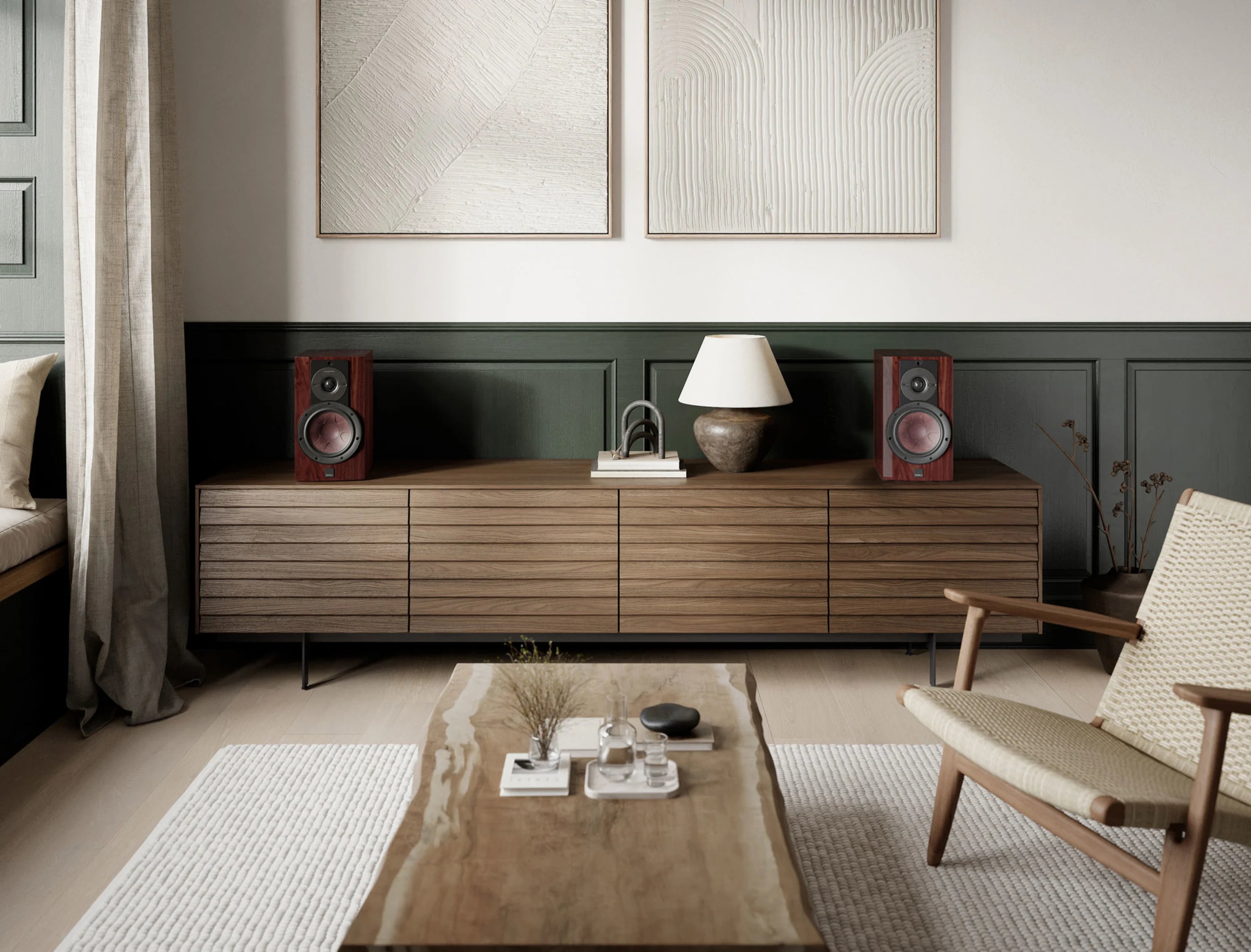 DALI Rubikore 2 passive bookshelf speakers shown in a modern living room setting, featuring sleek black design and compact size.