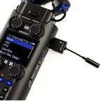 Zoom TCA-1 recorder accessory attached to a portable audio recorder, showing connection ports and compact design.