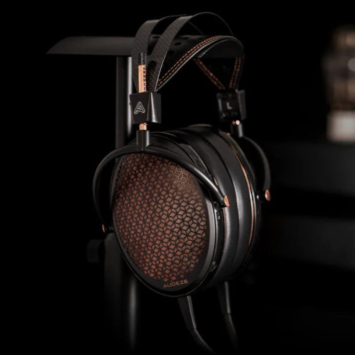 Audeze CRBN2 wired headphones shown in a lifestyle setting with black over-ear design and sleek branding.