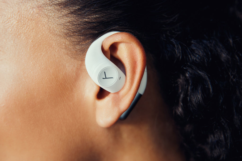 Close-up of white Beyerdynamic Amiron 200 wireless in-ear headphones worn by a woman.
