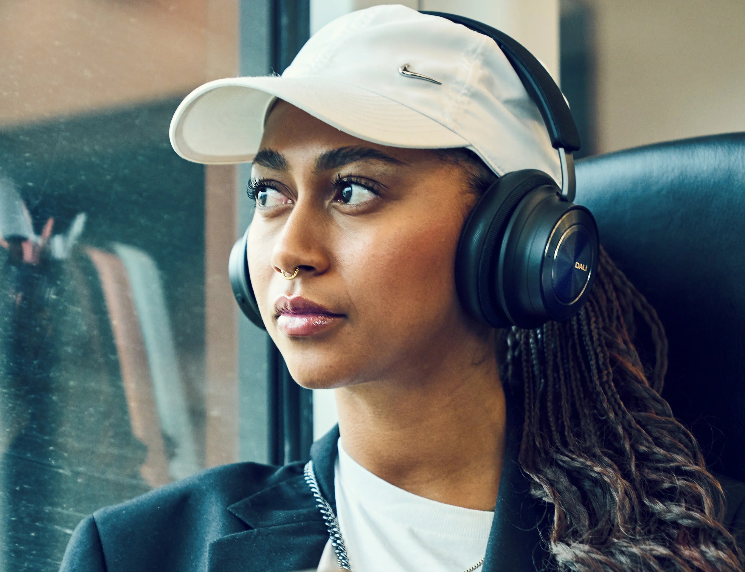 DALI Dali iO-8 wireless headphones worn by a woman on a train, showcasing sleek black design and comfortable fit.