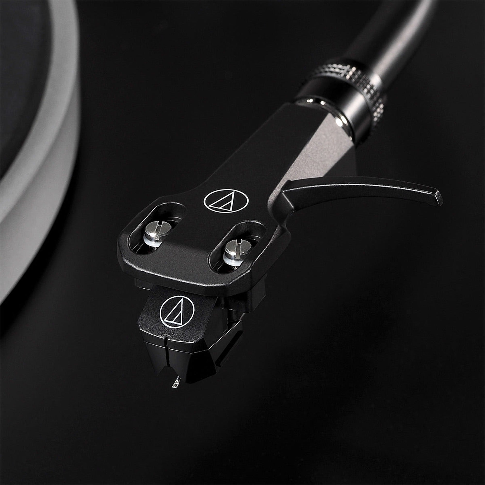 Audio-Technica AT-VM95EBK MM phono cartridge installed on a turntable, showcasing its black body and stylus in a lifestyle setting.