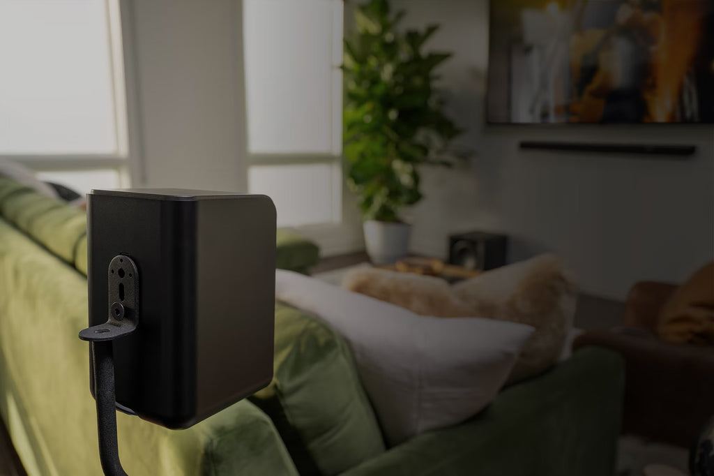 Klipsch Flexus SURR 100 soundbar behind a modern living room couch, showcasing its sleek design and placement in a home entertainment setup.