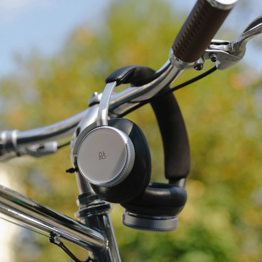 Wireless Bang & Olufsen Beoplay H100 headphones shown in a lifestyle setting with sleek, modern design and comfortable ear cushions.
