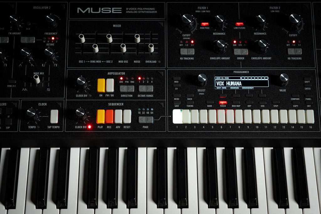 Moog Muse synthesizer with sleek black design featuring knobs and controls, displayed on a black background.