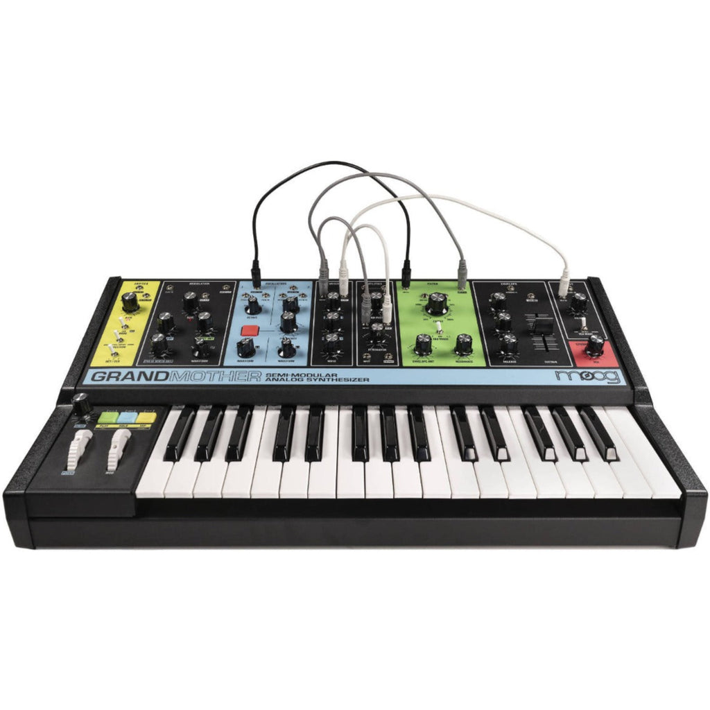 Moog Grandmother synthesizer with wooden sides and control knobs, showing its front panel and patch bay in a studio setting.
