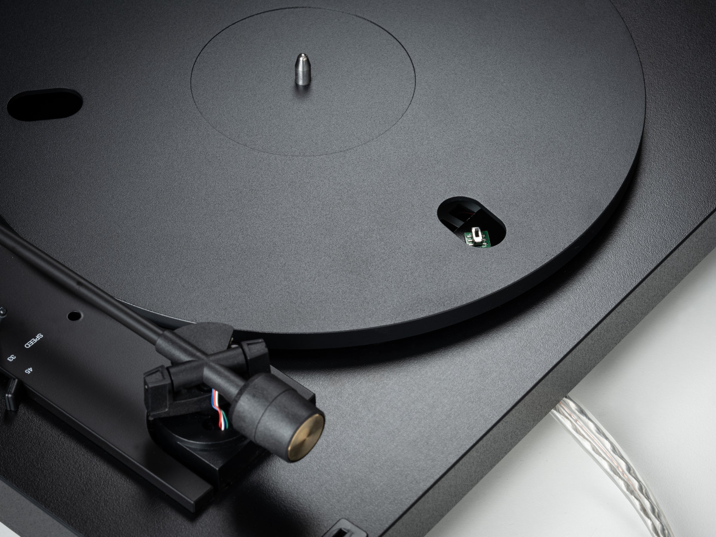 Pro-Ject Automat A1.2 turntable with sleek design, featuring a wooden plinth, tonearm, and platter, set in a stylish living room.