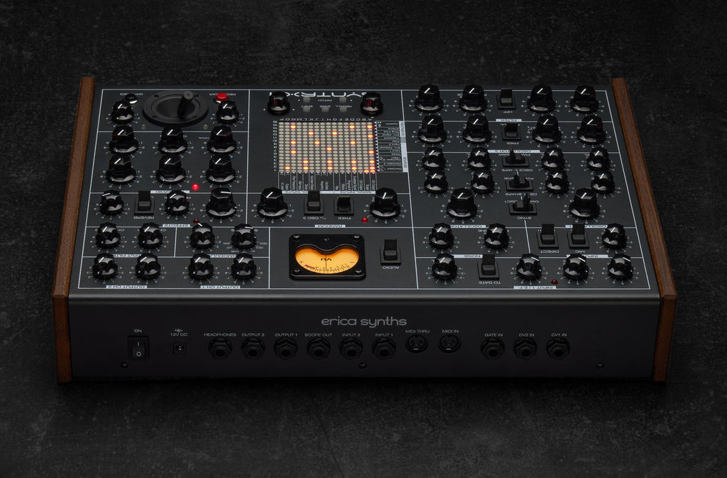 Erica Synths SYNTRX II desktop synthesizer with knobs, buttons, and colorful LED display on a black surface.