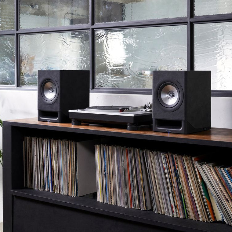 Black Technics SC-CX700 active bookshelf speakers with controls, positioned on a stand in an audio setup.