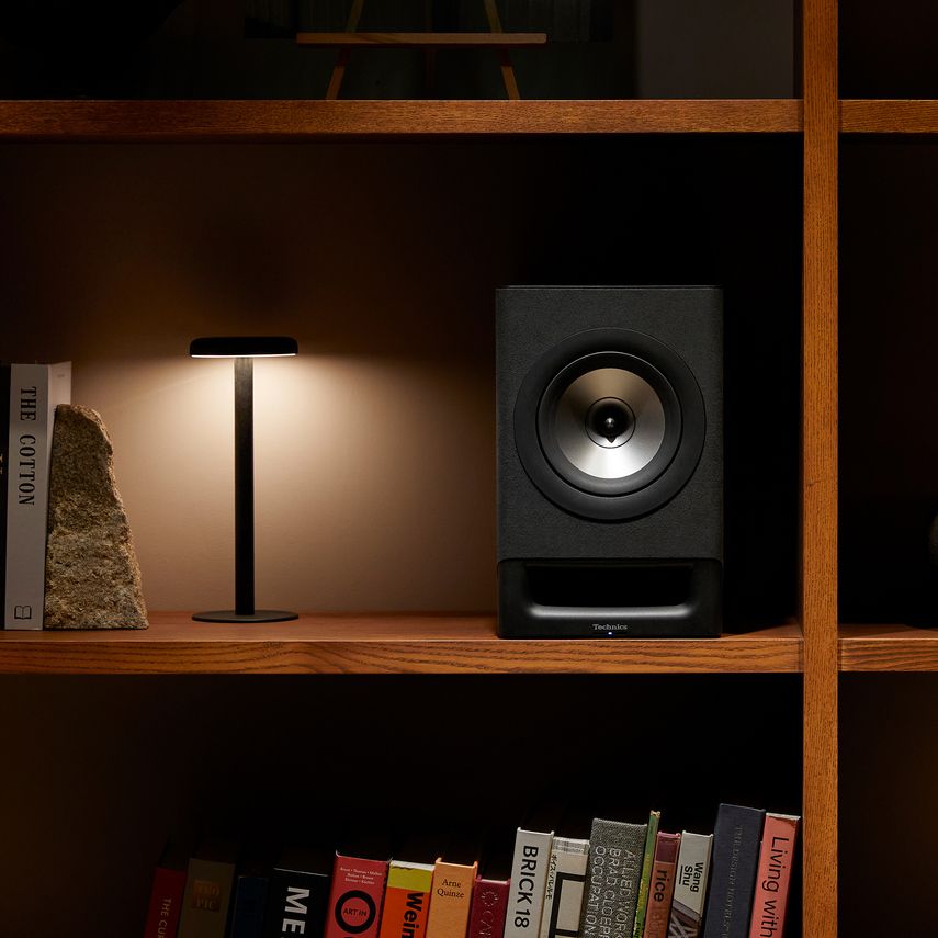 Black Technics SC-CX700 active bookshelf speakers on a stand with controls and connections visible.